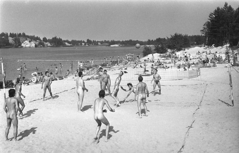 Black and white image of nudists playing volleyball on a beach