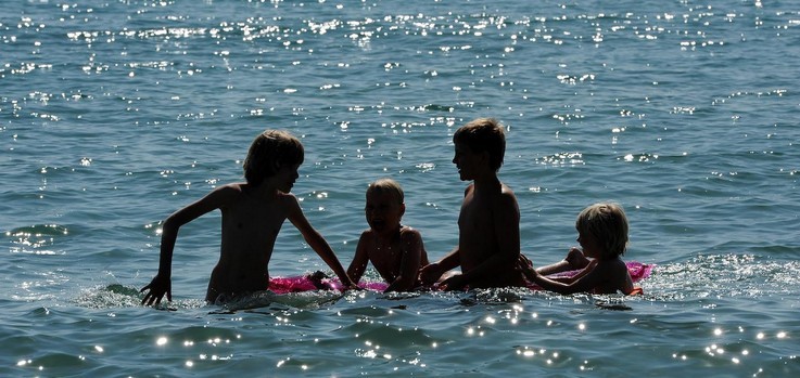 Children playing in the water. Backlit image.