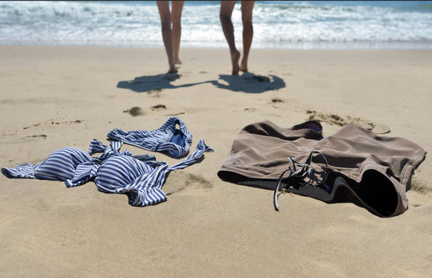 Nude legs walking away from clothes on the beach