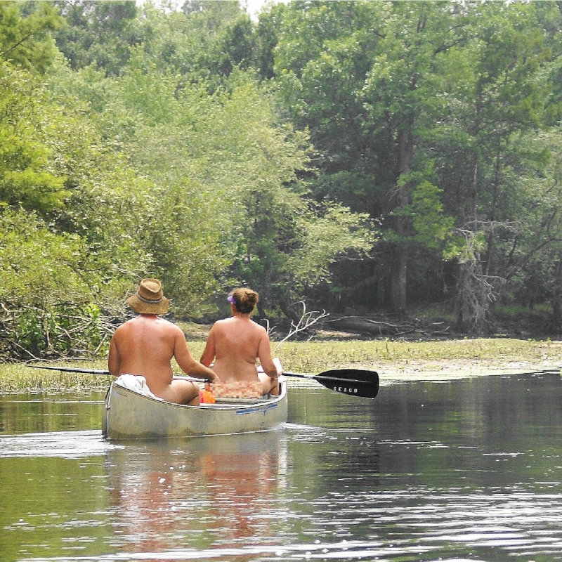 Naturists paddling along in a canoe