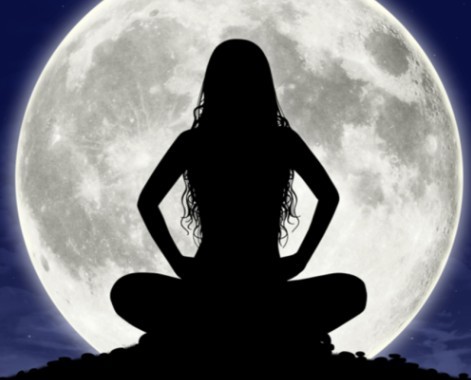 Nude woman meditating beneath the moon