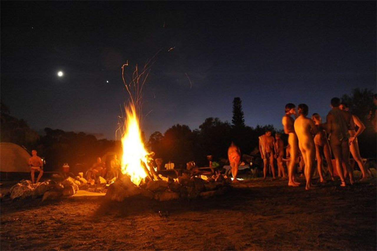 Nude folks near a nightly campfire